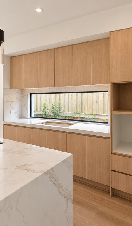 Natural oak kitchen detail with full-height cabinetry, a stone benchtop and integrated sink