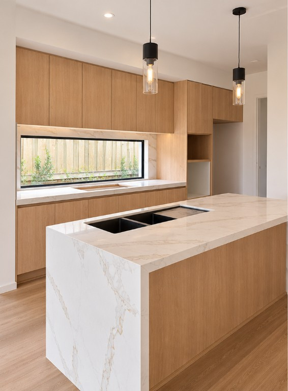 Natural oak kitchen in Melbourne with a veined stone waterfall island and a long window